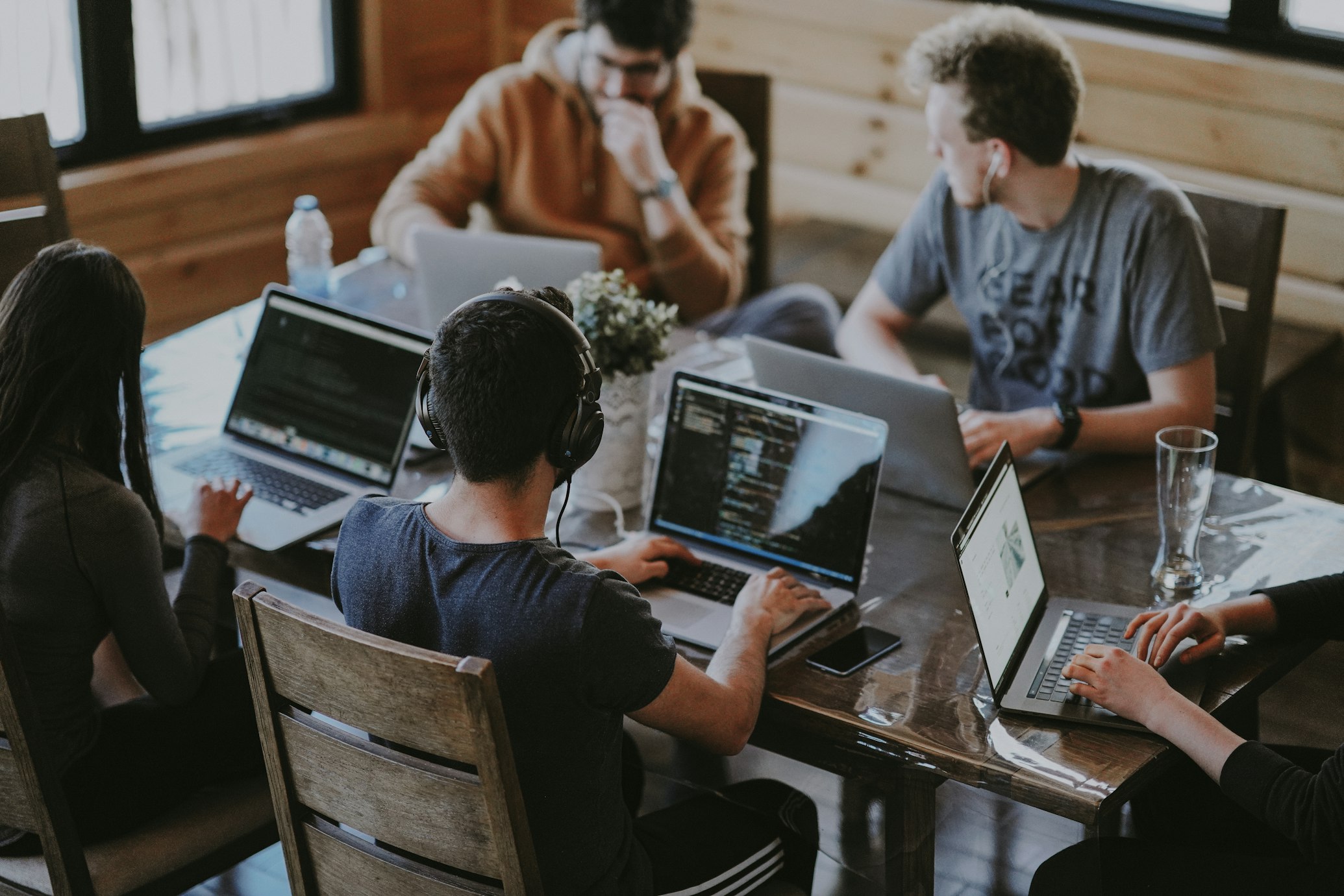 Diverse group of professionals working together on laptops in collaborative workspace